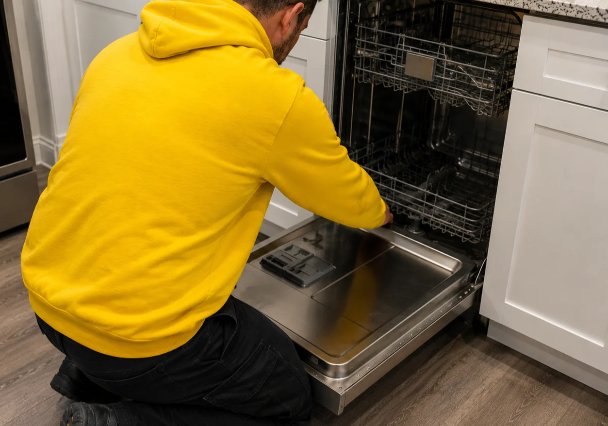 Dishwasher repair technician working on built-in dishwasher in Oakville home kitchen
